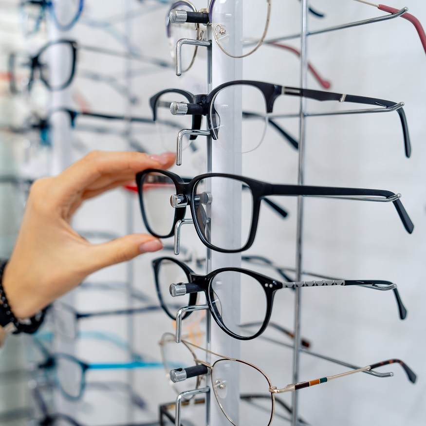 Pessoa analisando diversas marcas de óculos famosas em uma ótica.